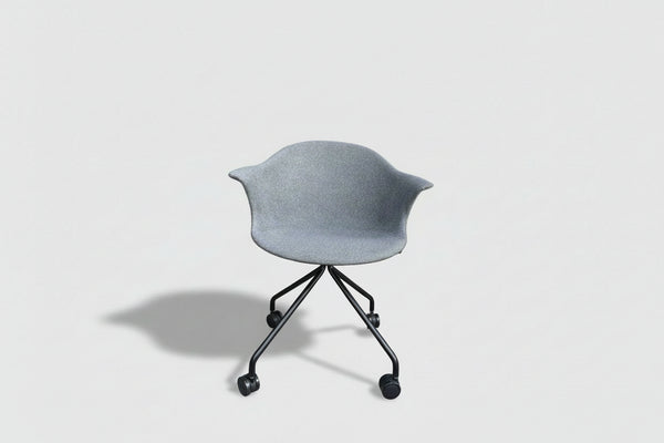 Gray leaf-shaped planter with a black stand against a building and window background
